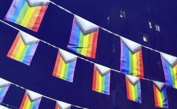 How to avoid rainbow washing in your Pride month campaign: picture is of the rainbow Pride event flags strung above the street in Manchester